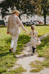 Senior woman holding hand of granddaughter walking at park - MASF41551