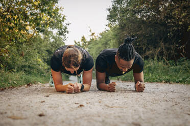 Determined man and woman doing plank on footpath - MASF41561
