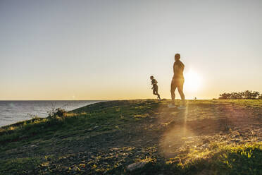 Women exercising on hill near sea at sunset - MASF41571