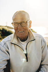 Portrait of smiling senior man wearing eyeglasses on sunset - MASF41587