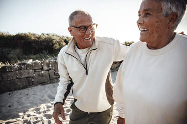 Happy senior couple walking together at beach - MASF41588