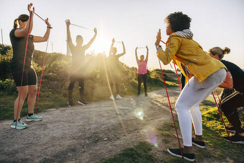 Team training together with resistance bands near footpath on sunny day - MASF41604