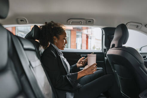 Side view of businesswoman using smart phone while sitting in car - MASF41632