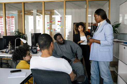 Businesswoman conducting meeting with male and female colleagues at office - MASF41671