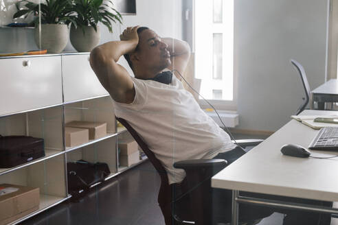 Overworked male entrepreneur with head in hand sitting on chair at office - MASF41678