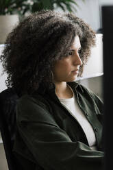 Focused businesswoman with curly hair working at office - MASF41683