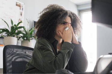 Worried businesswoman sitting with hands covering mouth at office - MASF41684