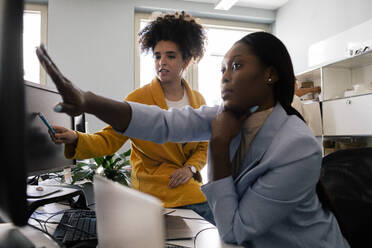 Businesswoman discussing with female colleague while working at coworking office - MASF41712