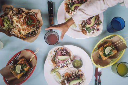 Directly above view of fresh tacos and snacks with drinks arranged on table at restaurant - MASF41789