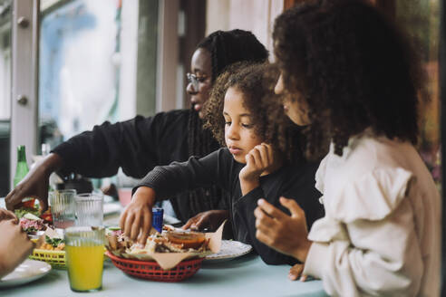 Girl having tacos with family at table in restaurant - MASF41795