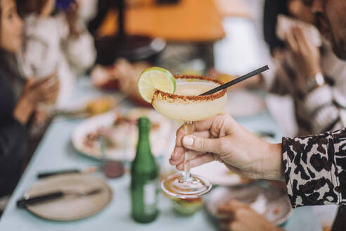 Hand of unrecognizable person holding margarita glass at restaurant - MASF41801