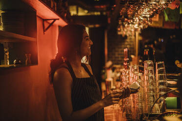 Smiling female bartender holding credit card machine while working at bar - MASF41817