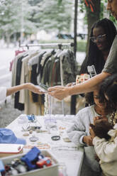 Man doing contactless payment while doing shopping near stall at flea market - MASF41827