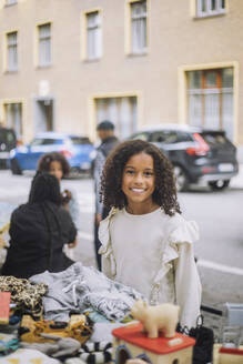Smiling girl with curly hair neat stall at flea market - MASF41836