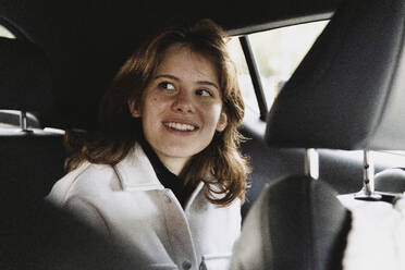 Smiling woman day dreaming while sitting in car on vacation - MASF41896