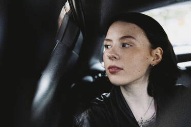 Female tourist looking through window while traveling car - MASF41898