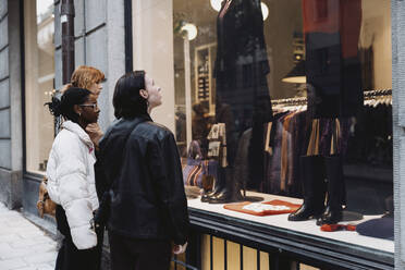 Multiracial female friends doing window shopping while standing at street - MASF41899