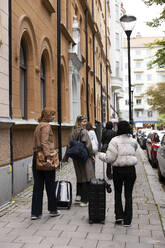 Multiracial female tourists walking with luggage on sidewalk in city - MASF41900