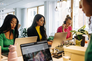 Businesswomen working together on laptops at desk in office - MASF41940