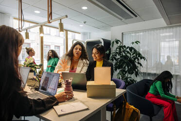 Multiracial female entrepreneurs discussing while working at office - MASF41948