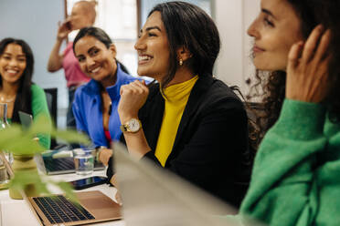 Smiling female business professional with colleagues during meeting at office - MASF41965