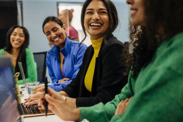 Happy female business professional with colleague during meeting at work place - MASF41966