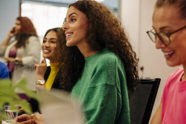 Smiling female entrepreneur discussing with colleagues in meeting at office - MASF41967