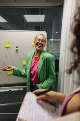 Happy businesswoman discussing while doing brainstorming with colleague at office - MASF41982