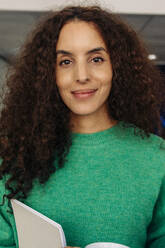 Portrait of smiling female entrepreneur with curly hair at office - MASF41996