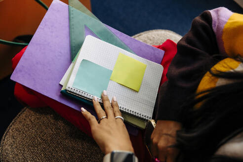 High angle view of businesswoman sitting with books at office - MASF42011