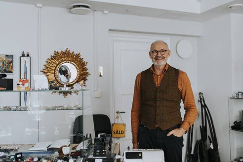 Portrait of smiling male owner with hand in pocket standing at store - MASF42026