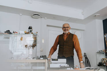 Portrait of smiling senior male entrepreneur standing in antique shop - MASF42027