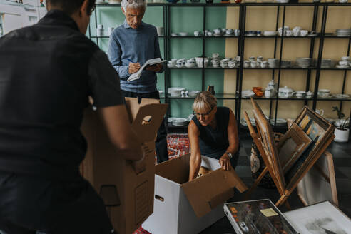 Female owner working with male colleagues in antique shop - MASF42048