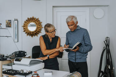 Female entrepreneur discussing budget with male colleague in antique shop - MASF42065