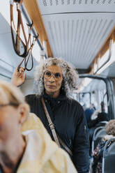 Contemplative female owner looking away while commuting through bus - MASF42070