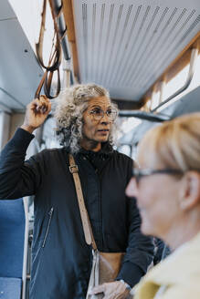 Contemplative female entrepreneur looking away while commuting through bus - MASF42073