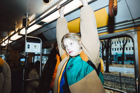 Girl holding handle while traveling in tram on weekend - MASF42157