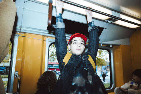 Portrait of boy holding handle while traveling in tram on weekend - MASF42159