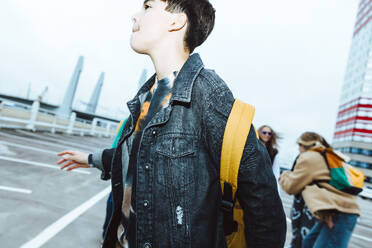 Boy standing by female friends on street against clear sky during weekend - MASF42189