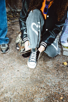 Low section of girl tying shoelace on footpath - MASF42198