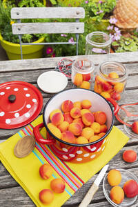 Preparation of apricot preserves on wooden garden table - GWF07980