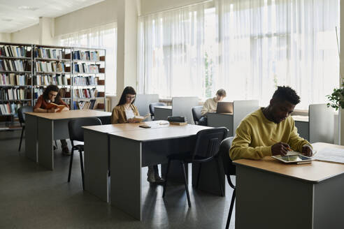 Studenten sitzen am Schreibtisch und lernen in der Bibliothek - DSHF01514