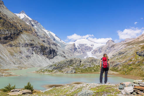 Frau steht auf einem Felsen am Sandersee vor den Bergen am Großglockner, Österreich - FOF13711