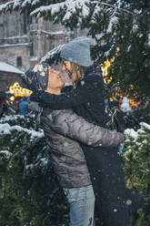 Happy man carrying woman near fir tree at Christmas market - TILF00054