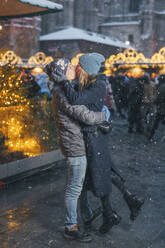 Mann trägt und küsst Frau auf dem Weihnachtsmarkt - TILF00059