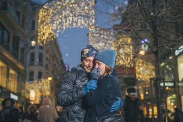 Ein glückliches Paar umarmt sich und hat Spaß auf dem Weihnachtsmarkt - TILF00065