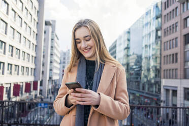 Glückliches Mädchen benutzt Smartphone in der Stadt - TAMF04048