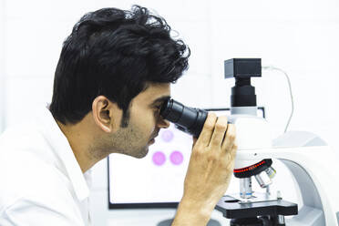 Microbiologist examining sample in microscope at laboratory - PCLF00881