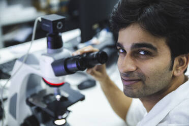 Lächelnde Wissenschaftlerin am Mikroskop im Labor - PCLF00883