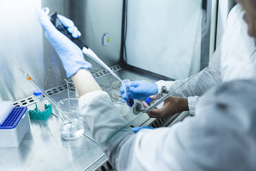 Scientist with colleague taking liquid solution with pipette - PCLF00888